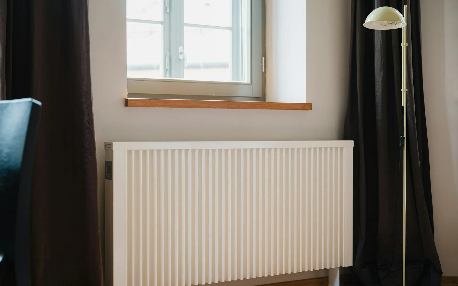 Termosifone bianco sotto una finestra in un appartamento a Milano.