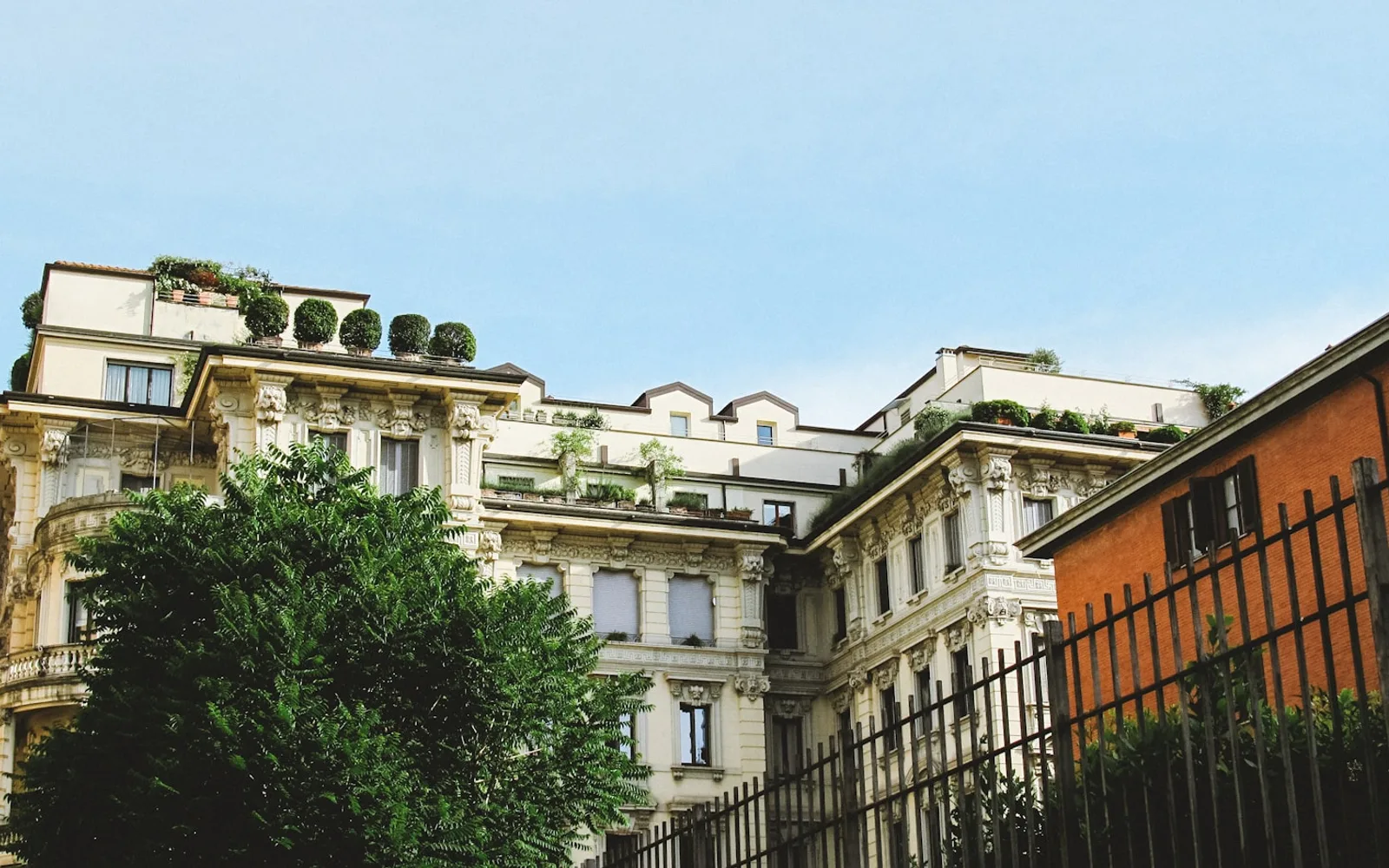 Facciata di un palazzo residenziale milanese con terrazzi e cornicioni.