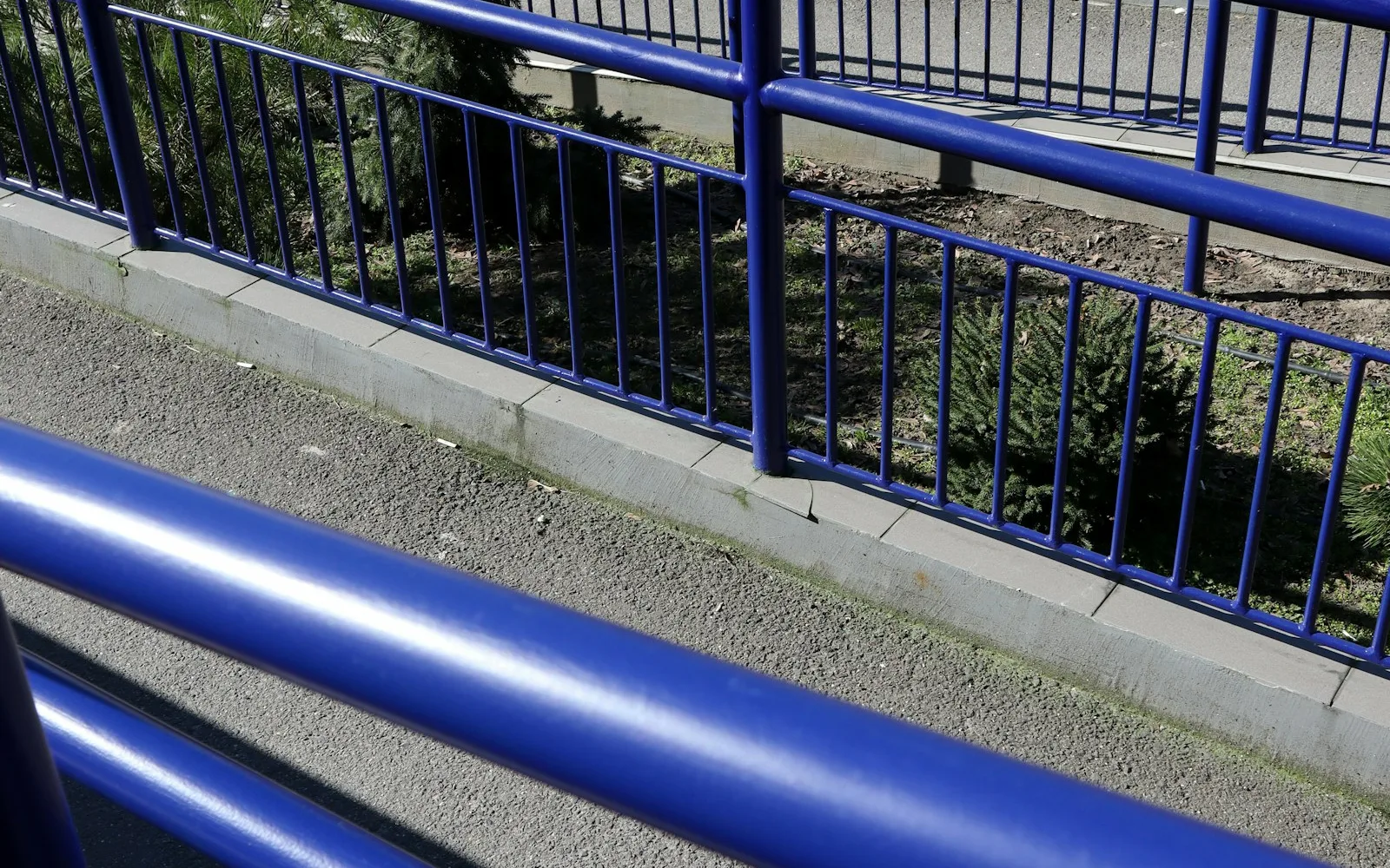 Rampa di accesso blu con corrimano che sale a zigzag lungo un percorso pedonale.