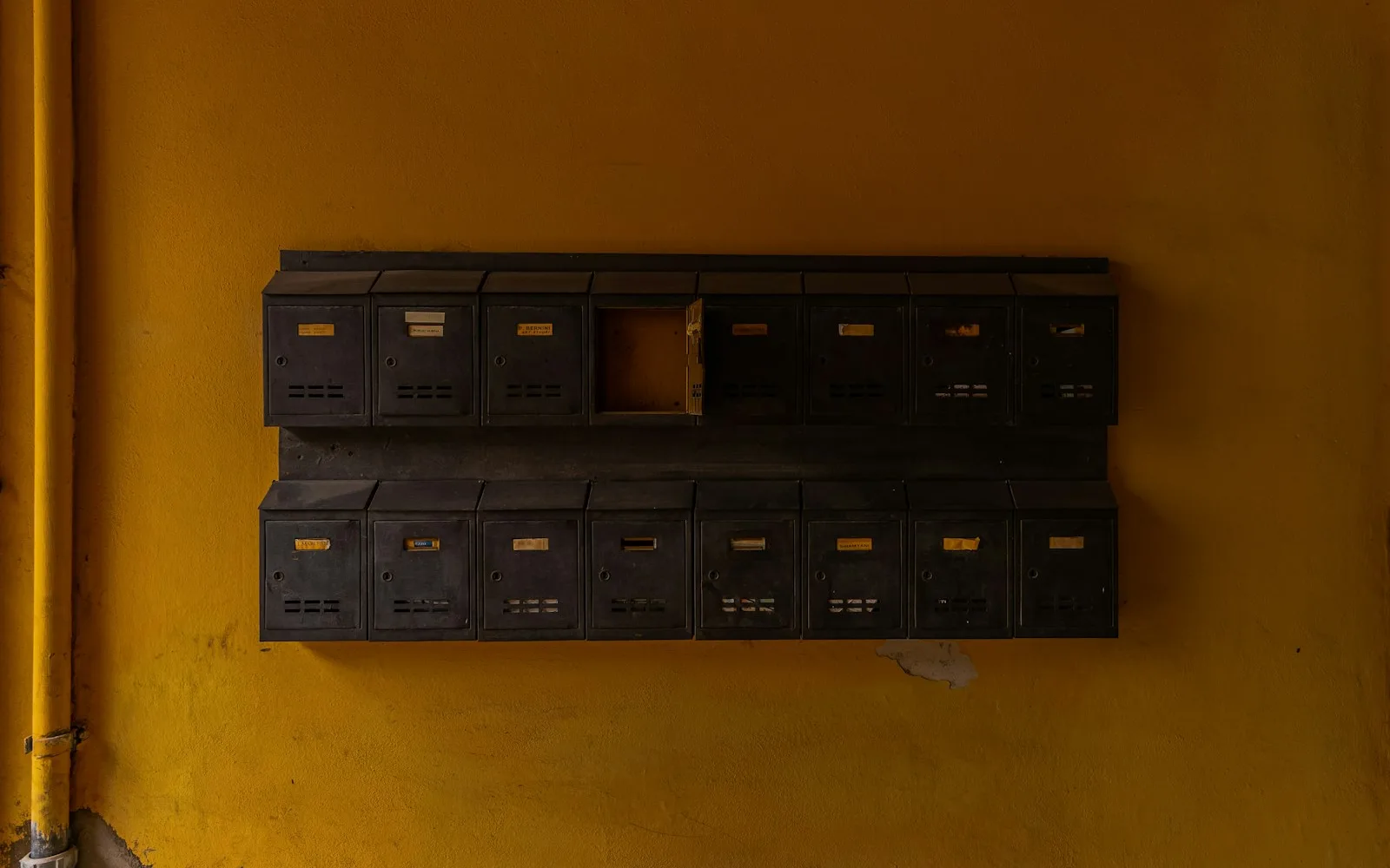 Fila di cassette postali metalliche nell’androne di un palazzo.