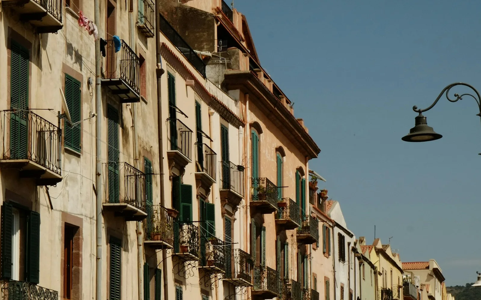 Fila di edifici residenziali italiani d'epoca con balconi in ferro battuto e persiane.