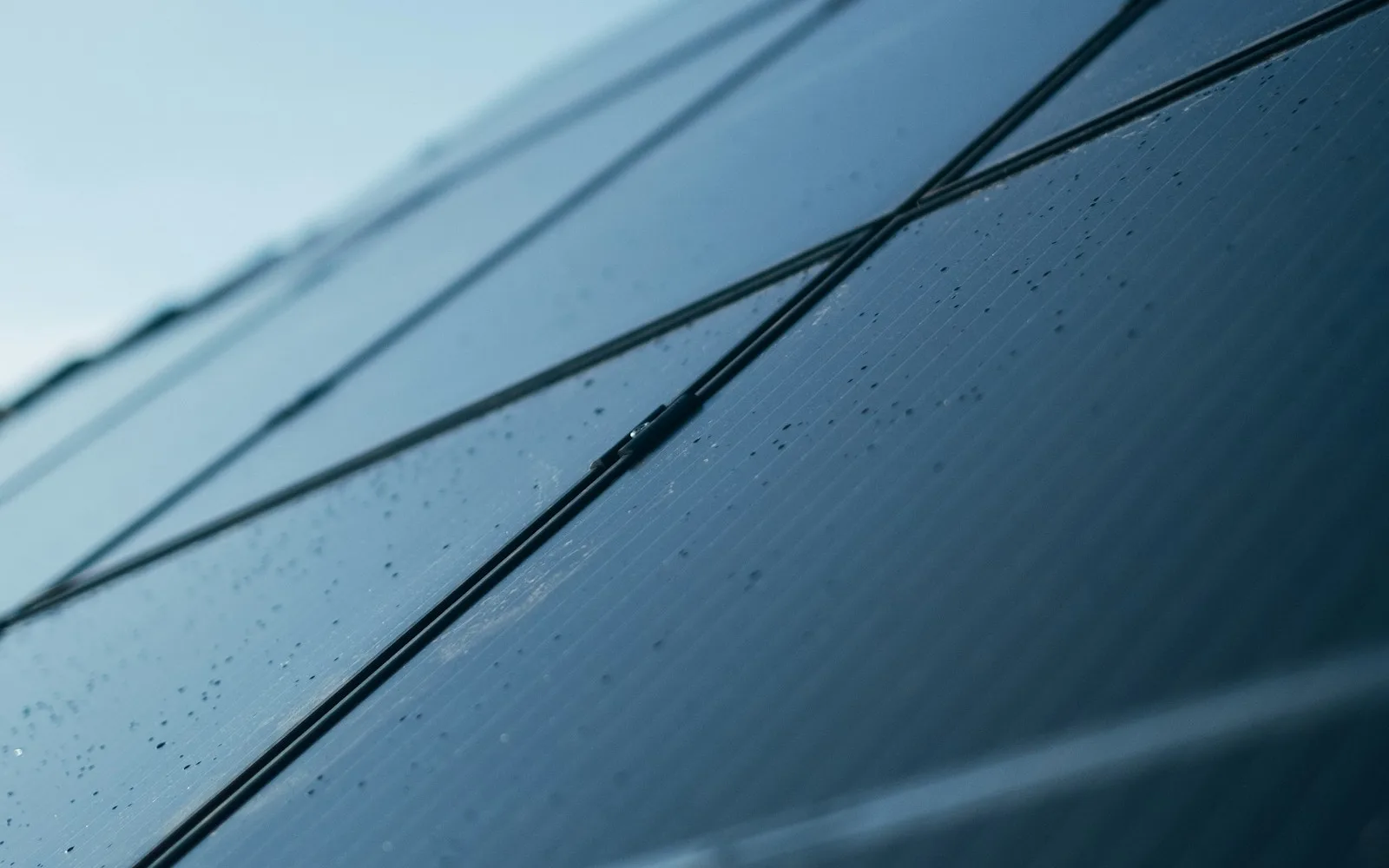 Pannelli fotovoltaici inclinati verso il cielo, ripresi da vicino sulla copertura di un edificio.