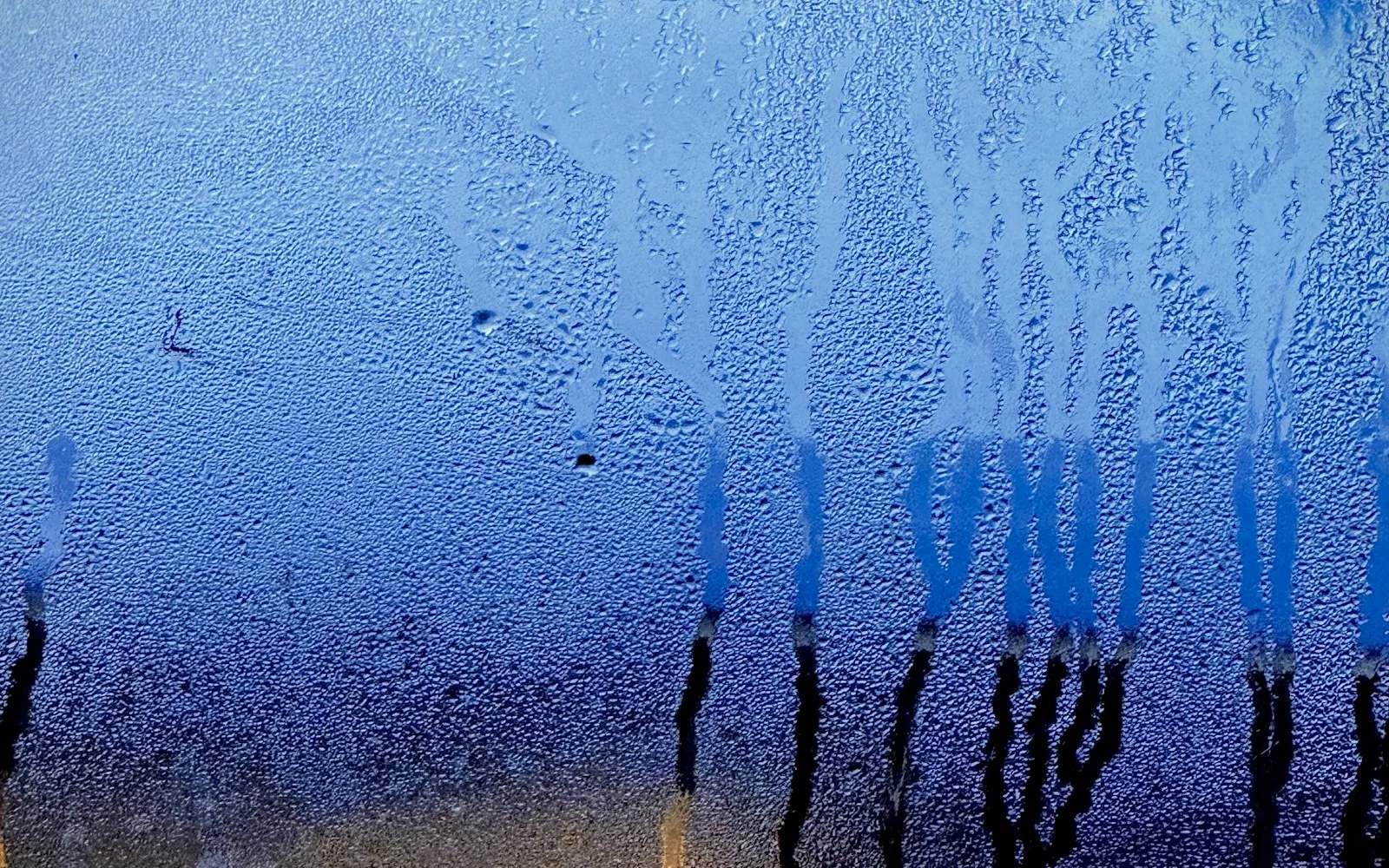 Condensa che cola lungo il vetro interno di una finestra di casa in una mattina fredda.