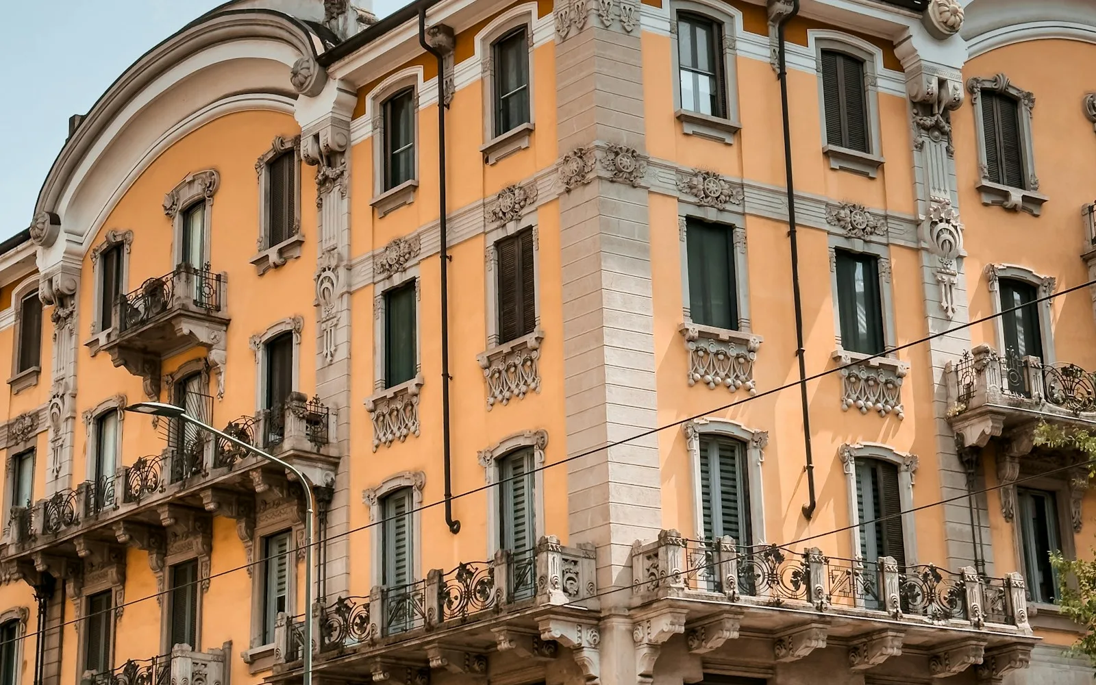 Palazzo milanese in stile Liberty con balconi decorati e una farmacia al piano terra.