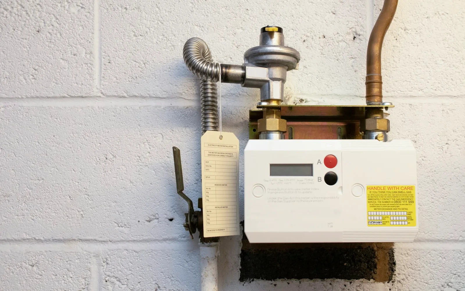 Contatore del gas con riduttore di pressione e un cartellino di identificazione appeso.