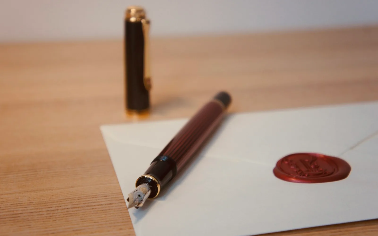 Una penna appoggiata su una lettera con un timbro rosso.