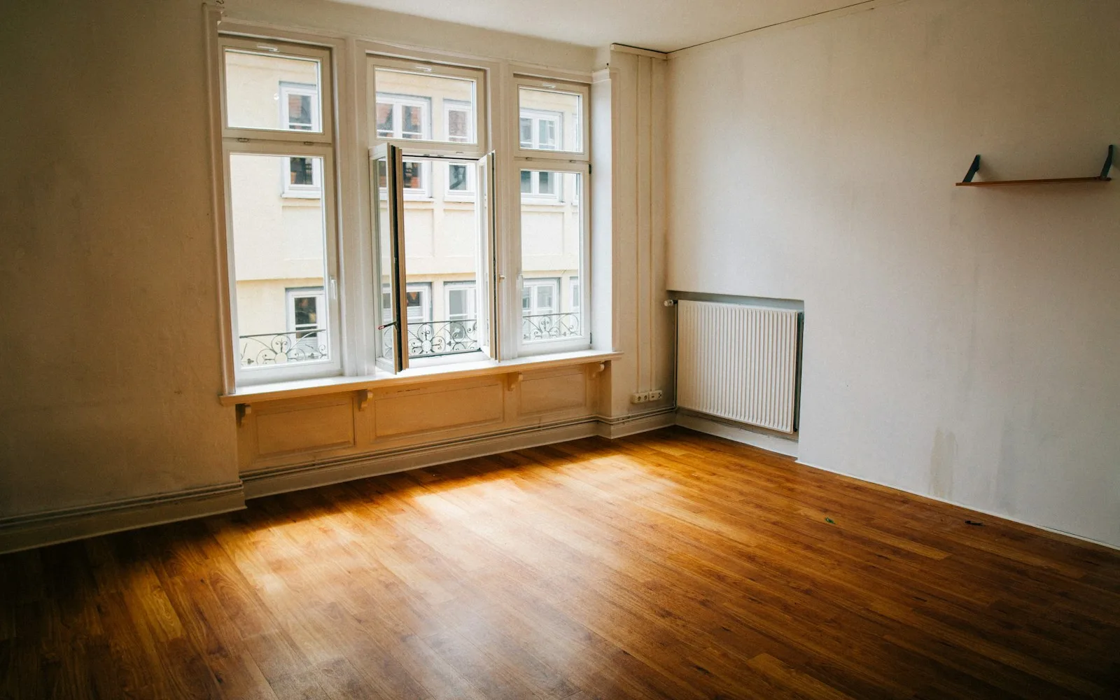 Stanza vuota con parquet e finestre alte al momento della riconsegna dell'appartamento.