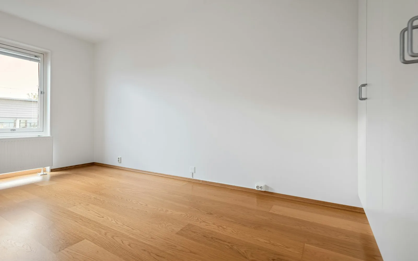 Stanza vuota con parquet e finestra, al termine di una locazione.