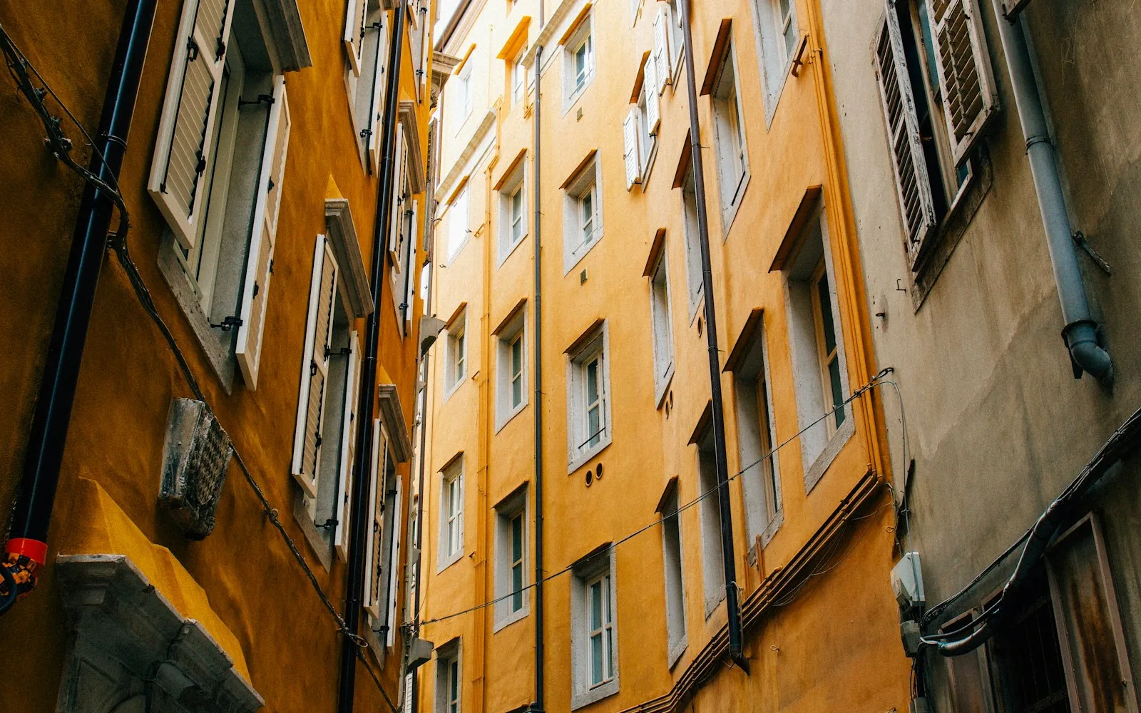 Due palazzi residenziali italiani con persiane affacciati l'uno sull'altro lungo una via strettissima.