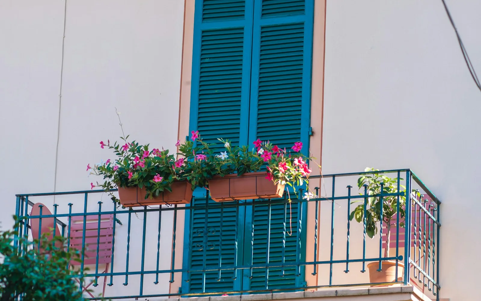 Balcone con persiane e fiori di un appartamento in affitto in un palazzo italiano.