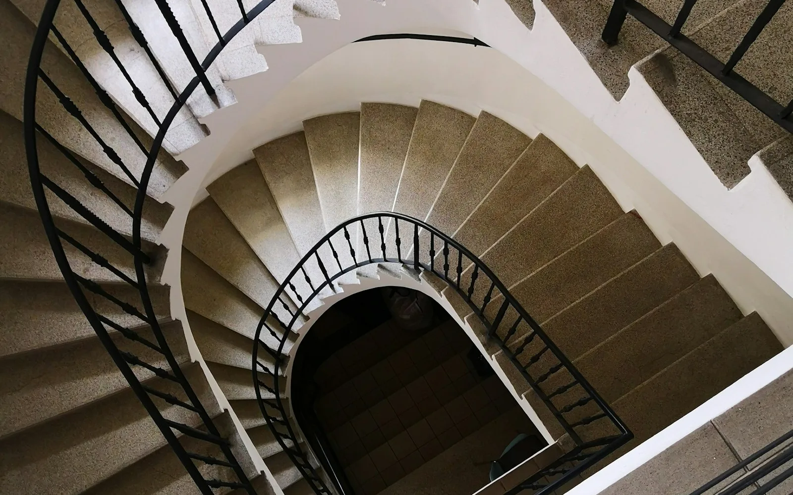 Scala a chiocciola con ringhiera in ferro battuto in un palazzo residenziale.