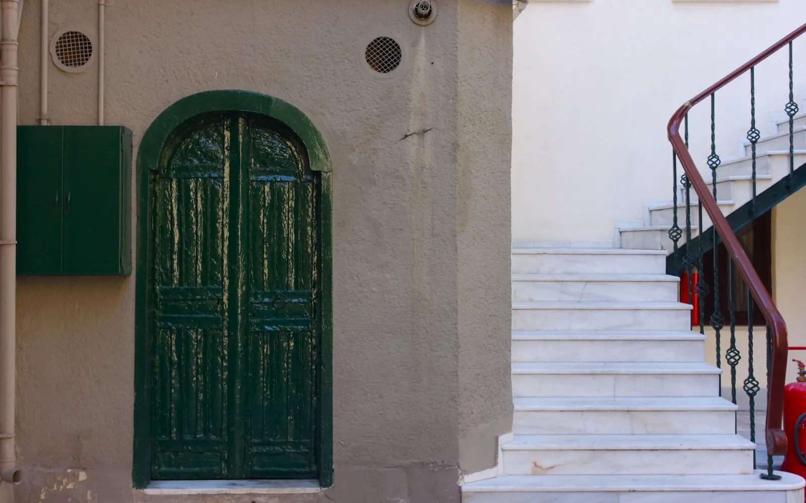 Androne d'ingresso di un palazzo d'epoca a Milano, con scala in marmo e ringhiera in ferro battuto.