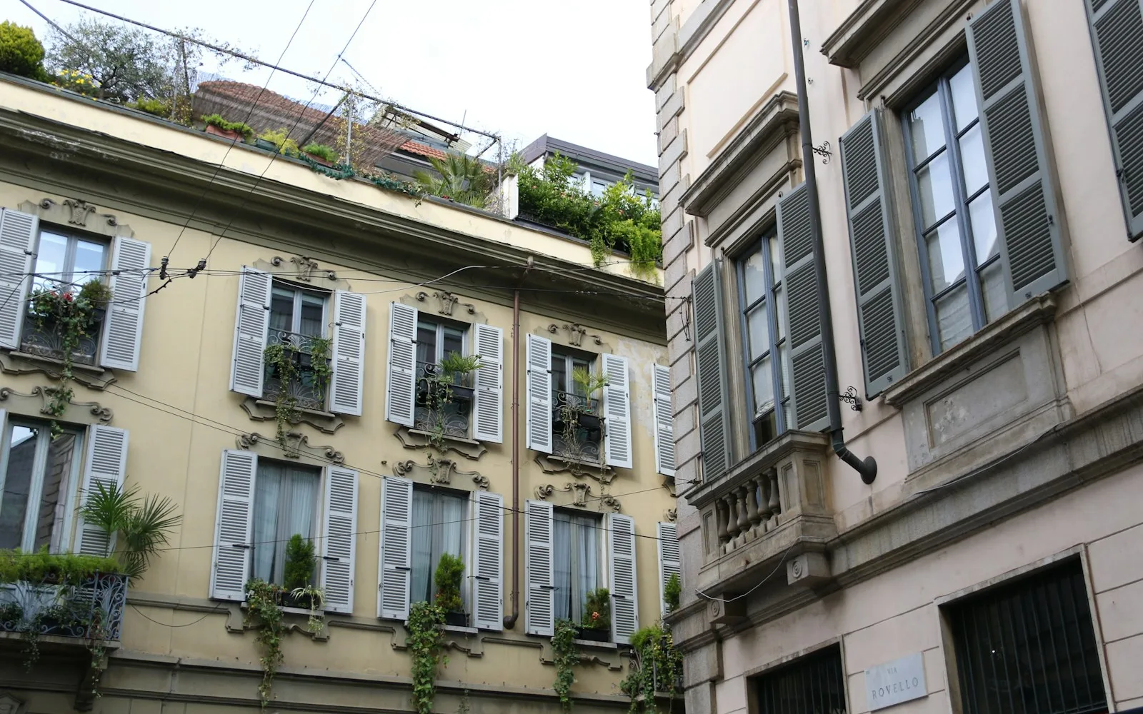 Facciata di un palazzo residenziale milanese con persiane e balconi.