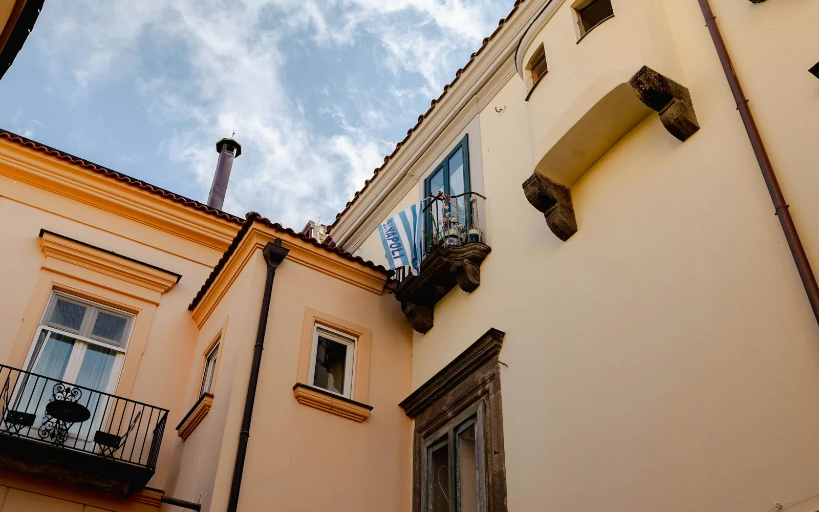 Facciate di palazzi italiani con balconi, persiane e cornicioni viste dal basso.