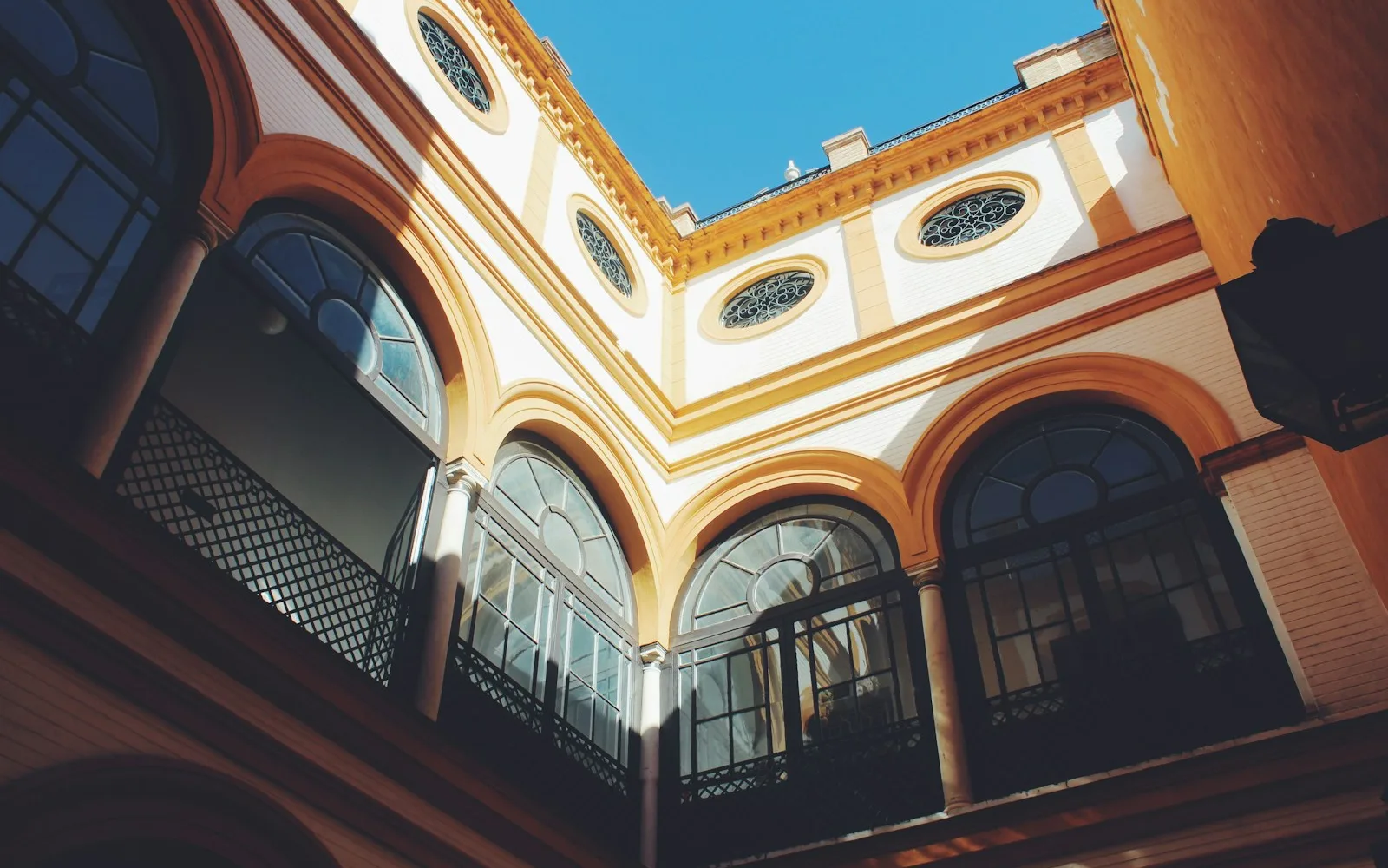 Cortile interno di un palazzo con archi e ampie finestre.
