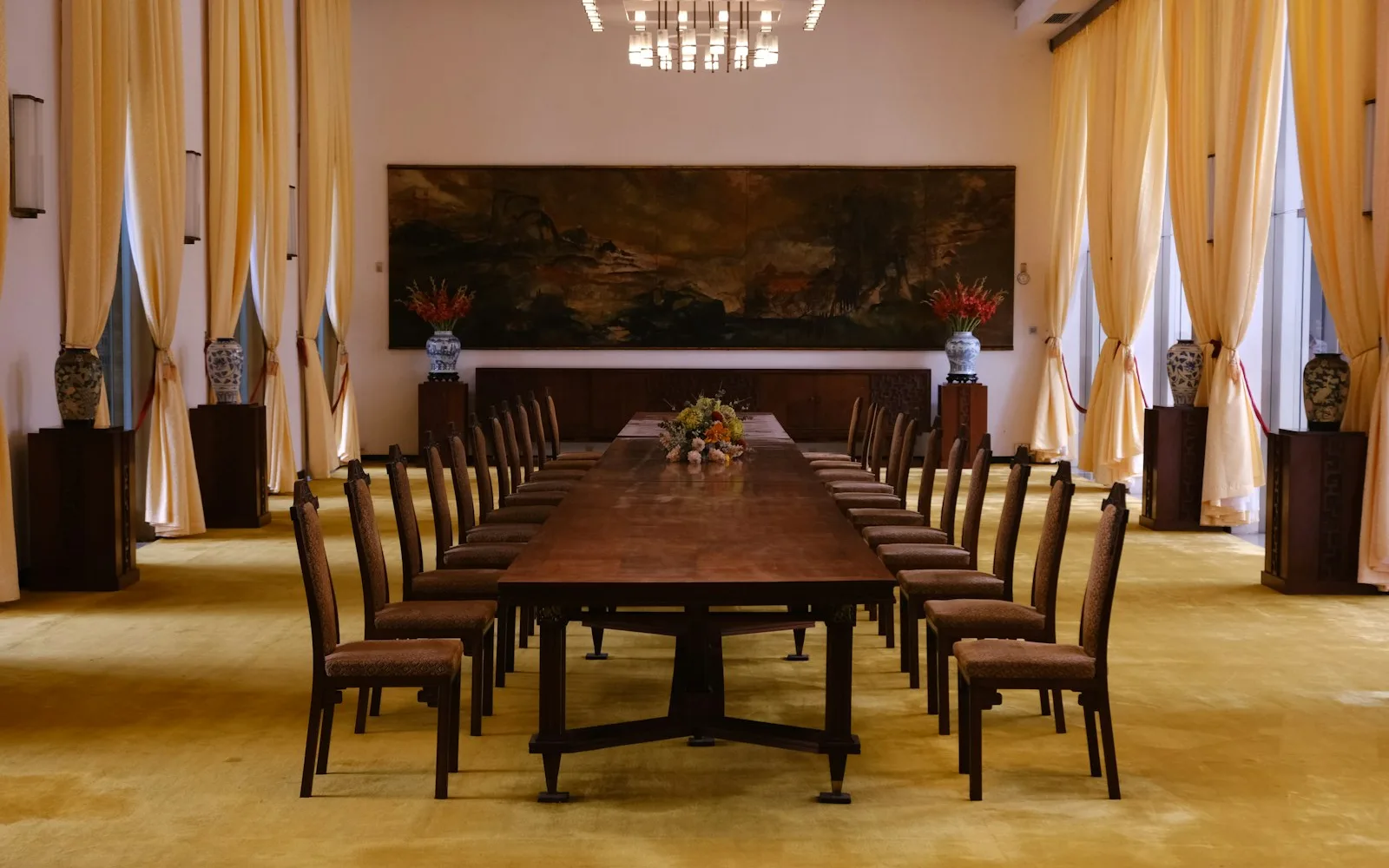 Sala assembleare con un lungo tavolo e sedie disposte per la riunione.