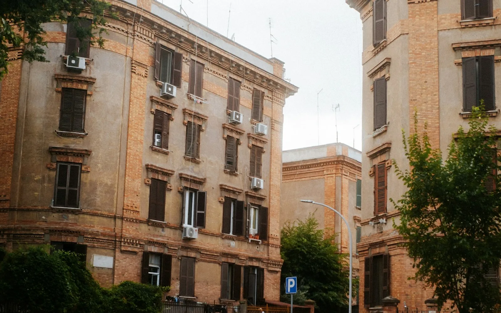 Due palazzi residenziali distinti in mattoni a Roma, separati da uno stacco visibile tra le facciate.