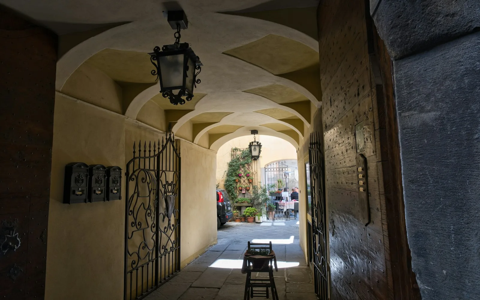 Androne voltato di un palazzo italiano con cancelli in ferro battuto aperti sul cortile interno.