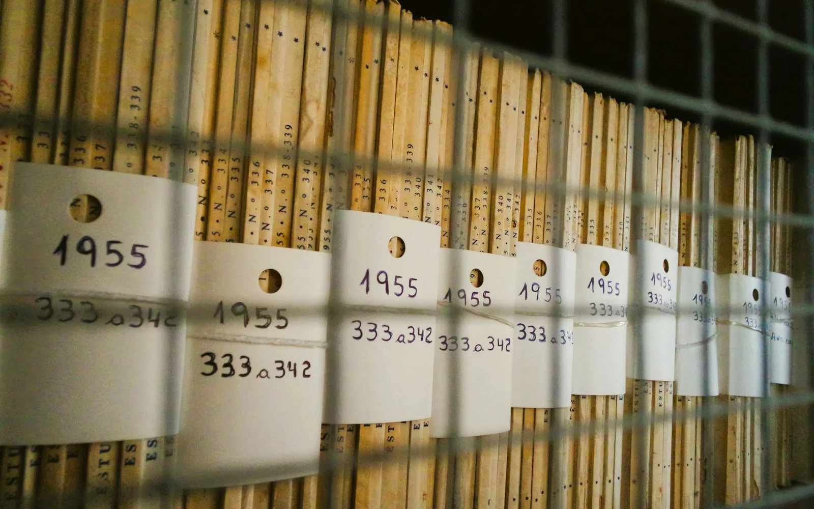 Scaffale di archivio con registri numerati e cartellini con l'anno sul dorso.